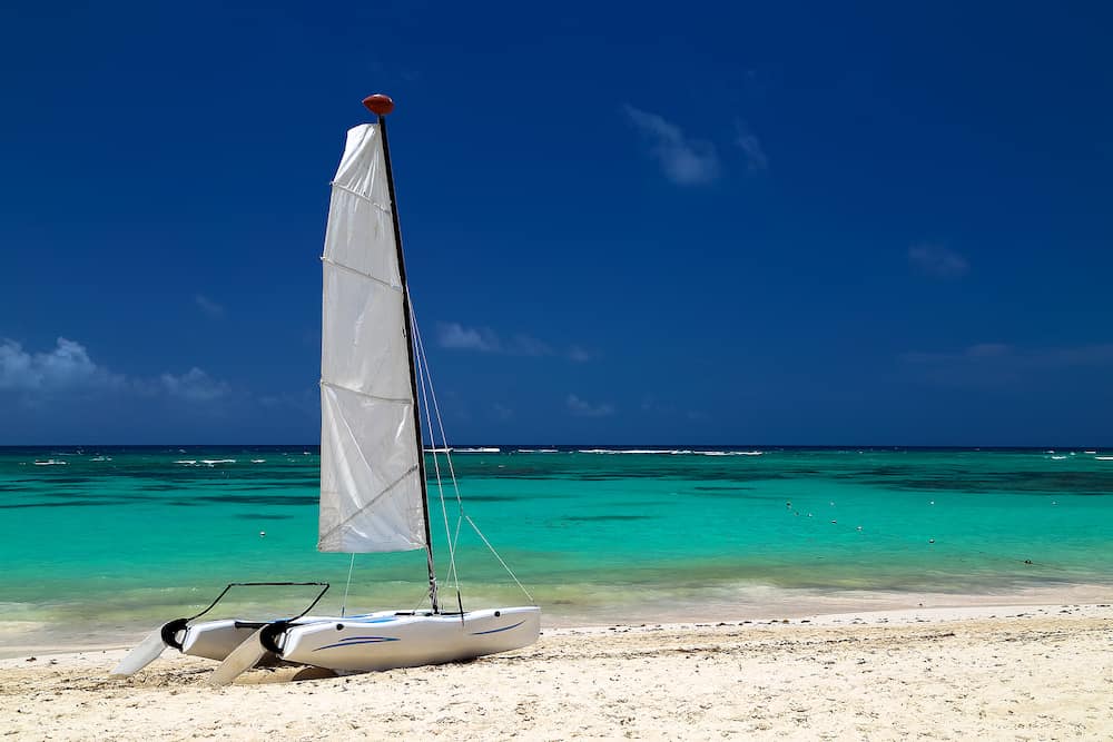 Catamaran on the exotic coast of the Atlantic Ocean with a background from golden sand of emerald water and the blue sky. Beautiful Carribean sea, panoramic view from the beach. Picture with copy space.