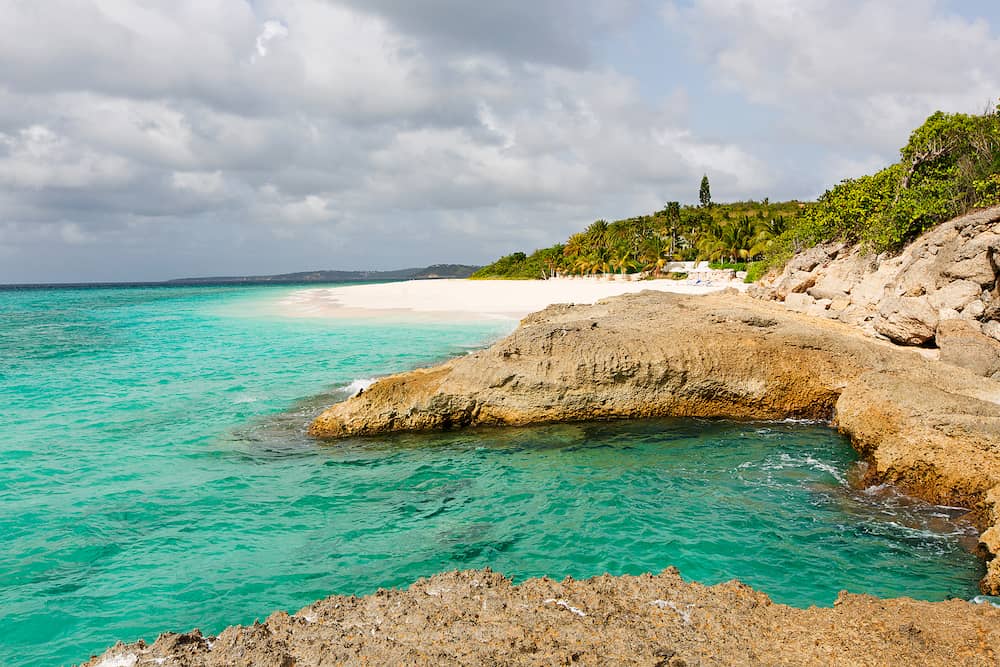 view at rugged rocky seashore and white sand empty beach at anguilla island in caribbean sea