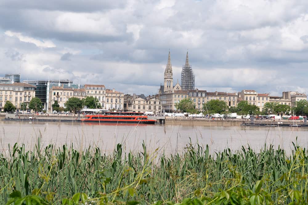 Bordeaux, Gironde / France - Garonne river riverside with red boat in Bordeaux city, France