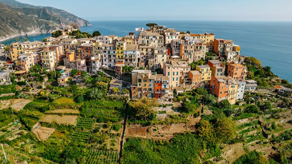 Aerial view of Corniglia and coastline of Cinque Terre,Italy.UNESCO Heritage Site.Picturesque colorful village on rock above sea.Summer holiday,travel background.Italian Riviera landscape.Steep cliff.