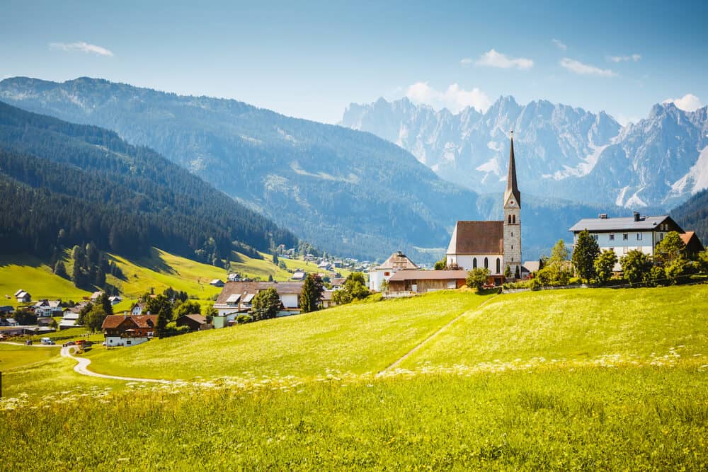 Picturesque touristic alpine village with Pfarrkirche Catholic church on a sunny day. Location place Gosau village, Upper Austria, Europe. Summer trip. Photo wallpaper. Discover the beauty of world.
