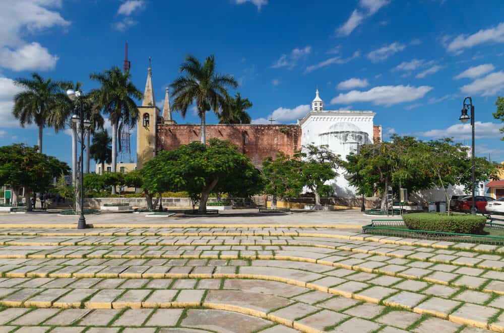 Santa Ana park and church with tropical trees with sunny blue sky, Merida, Yucatan, Mexico