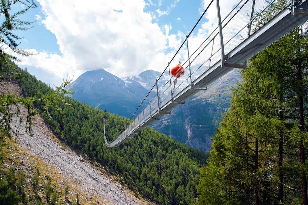 Charles Kuonen suspension bridge in Swiss Alps. With 494 metres, it is the longest suspension bridge in the world in summer landscape in blue sky