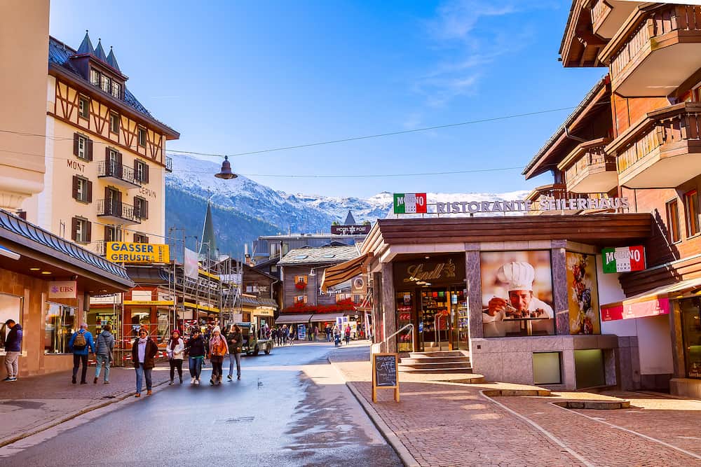 Zermatt, Switzerland - Town main street view in famous swiss ski resort, colorful traditional houses, mountains and people