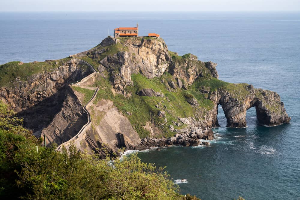 Walking on stone footpath to famous landmark and film location in North of Spain, ocean islet with chapel San juan de Gaztelugatxe, Basque Country, Spain