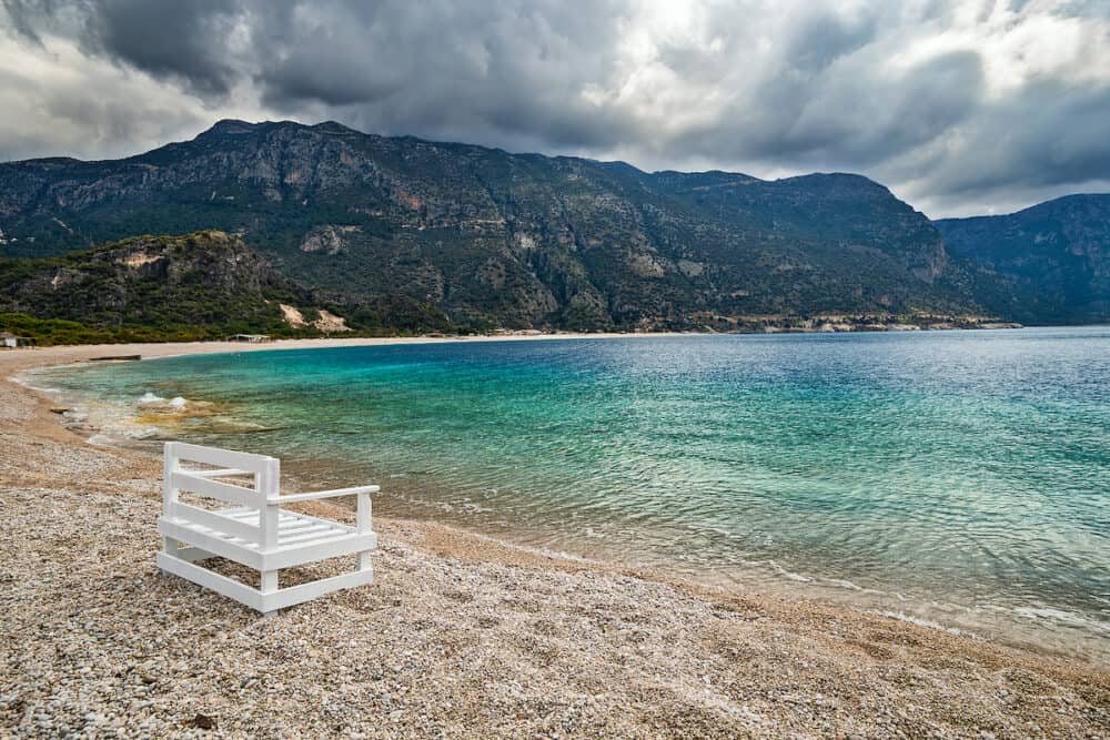 Empty Oludeniz beach out of season on the background of the mountains in pre-thunderstorm weather. Mugla, Turkey.