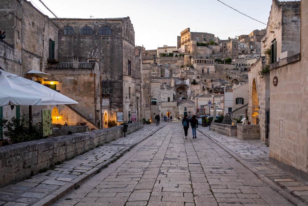 Matera, Italy - Evening view of the city of Matera, Italy, with the colorful lights highlighting patios of sidewalk cafes in the Sassi di Matera a historic district in the city of Matera. Basilicata. Italy