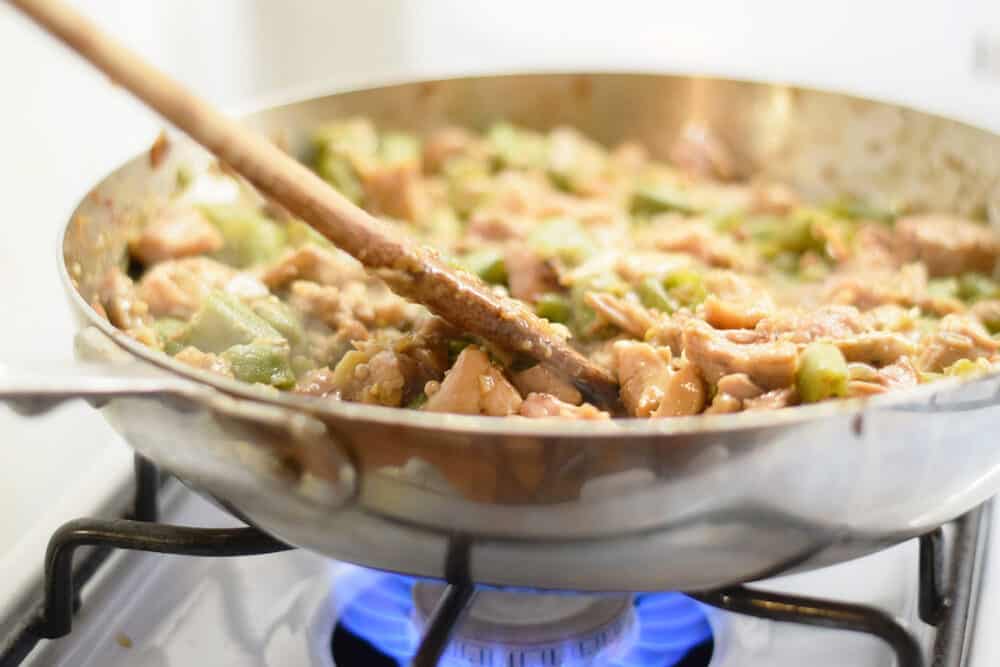 Wooden spatula stirring frango com quiabo (Portuguese for "chicken with okra") Brazilian dish cooking in saute pan on stove