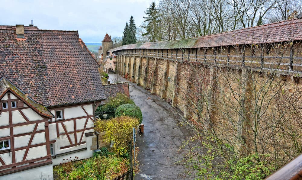 Ancient stone wall surrounding the old town from the wall. Medieval half-timbered house with tile roof. German architecture. Germany. Bavaria. Rothenburg ob der Tauber