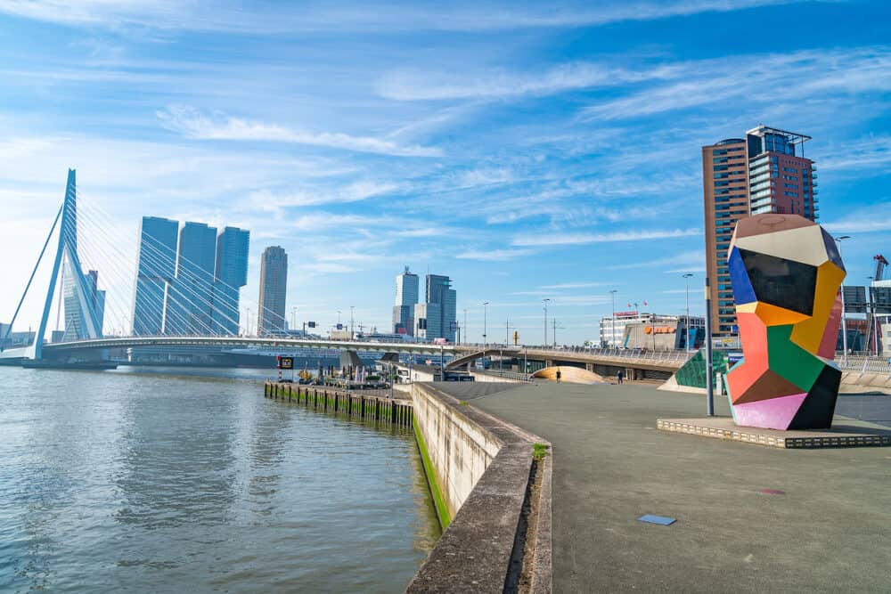 Rotterdam Netherlands - Waterfront with colorful abstract sculpture named Marathonbeeld toward Erasmus bridge with De Rotterdam modernist high-rise in background..