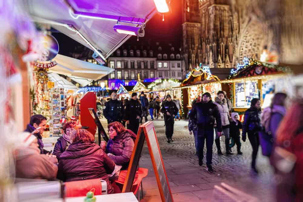 STRASBOURG, FRANCE - Wide image of People enjoying ca cafe and sweets in central Place de La Cathedrale with locals and visitors admiring the Christmas Market in Place de la Cathedrale