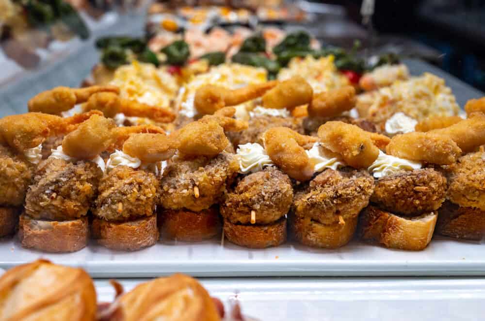 Typical snack of Basque Country, pinchos or pinxtos, small piece of bread with different fish and sea food  toppings, served in bar in San-Sebastian or Bilbao, Spain