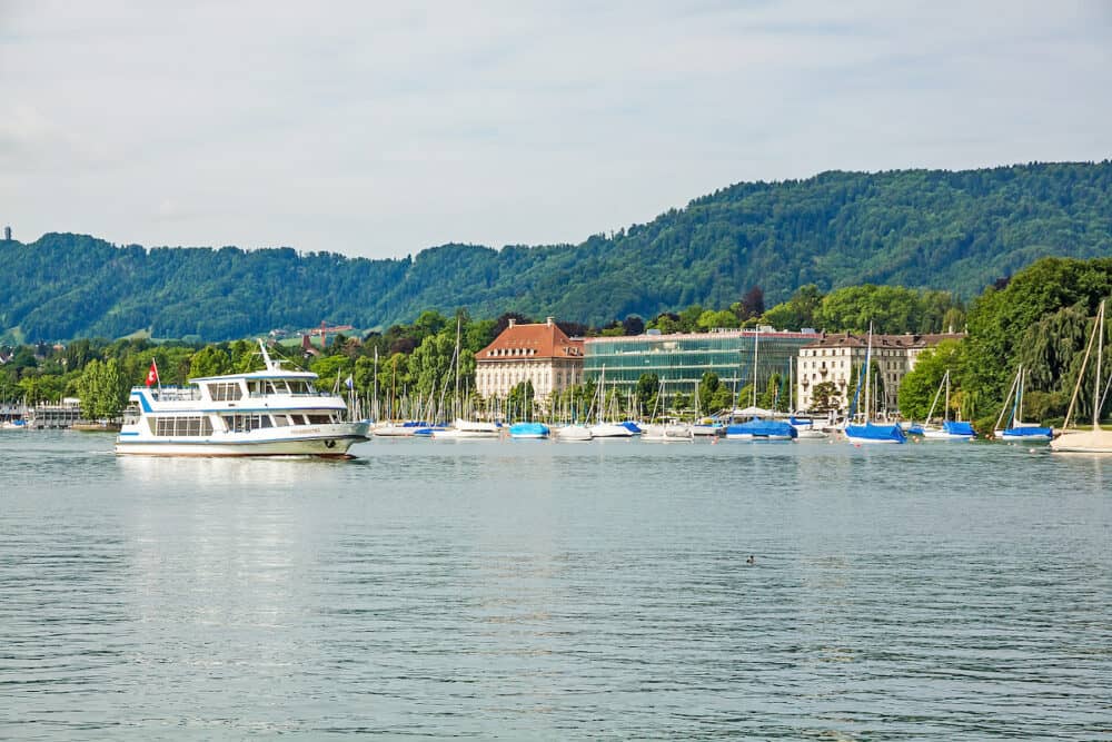 Zurich Switzerland -  Excursion boat arriving at shipping pier Burkliplatz. Western bank of Lake Zurich Mythenquai / Enge in background.