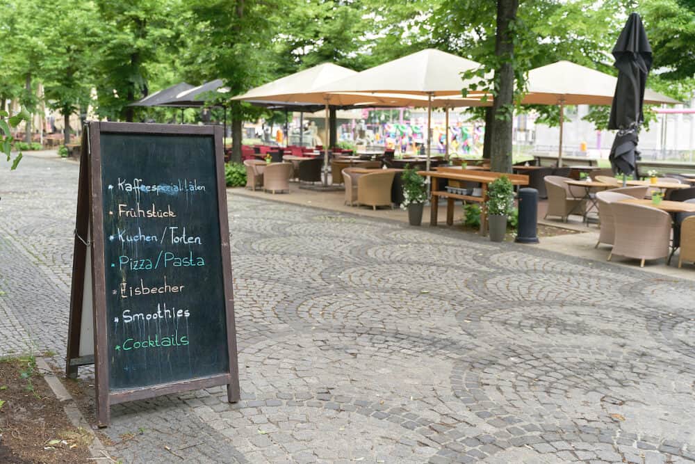 Chalkboard with the current offers like breakfast, cake, pizza, or cocktails in front of a cafe in the center of Berlin