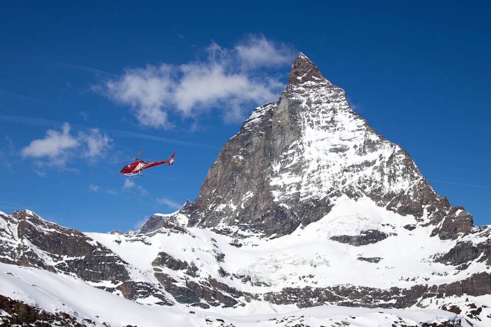 Zermatt, Switzerland -  A red rescue helicopter flying next to the famous Matterhorn