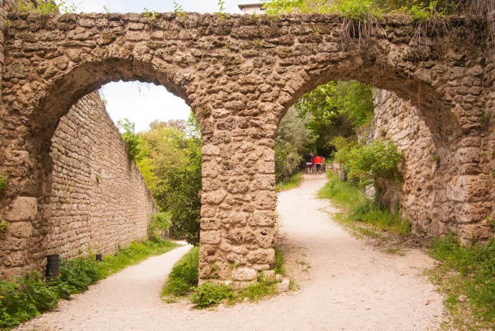View of dirt street and two old arches in the middle of park of Gubbio