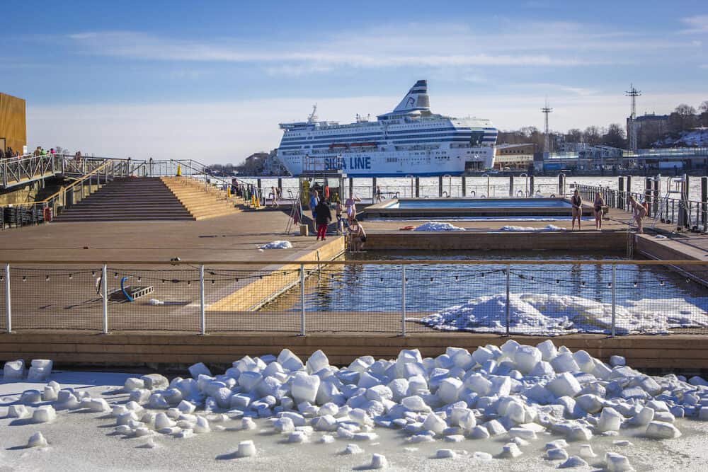 HELSINKI, FINLAND -  Allas Sea Pool- spa & wellness hub with large pools with sea warm water and saunas for relax in South Harbour of Helsinki, in winter sunny day, passenger ferry in the background, Finland.