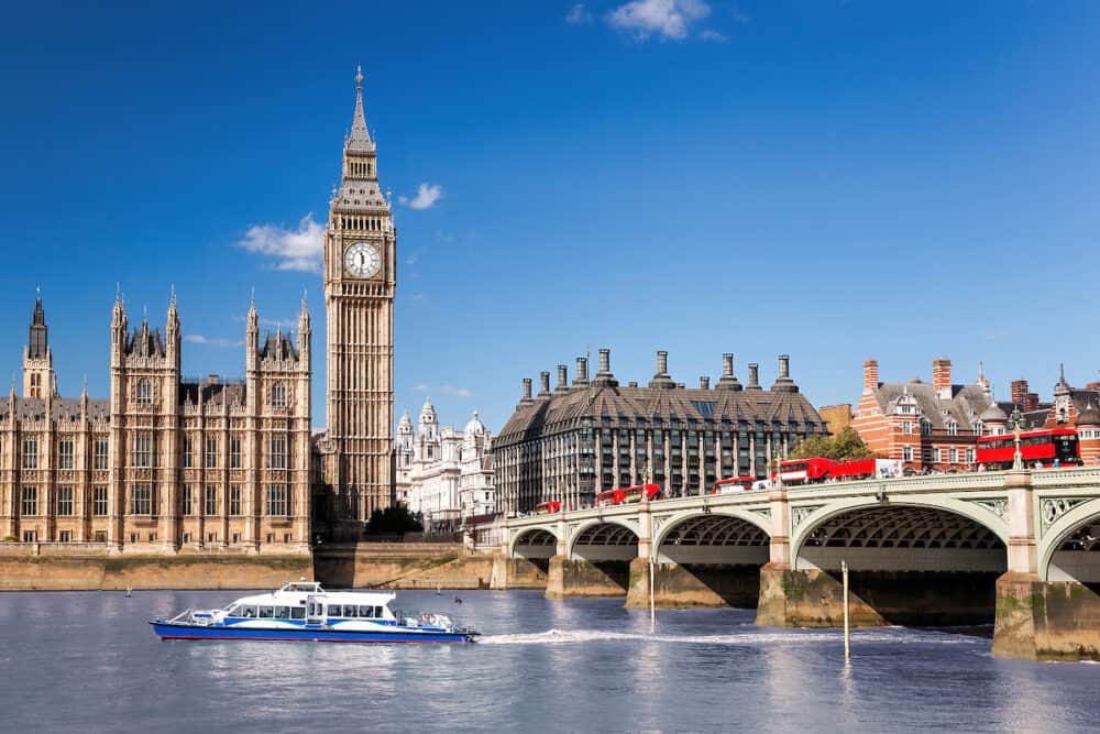 Famous Big Ben with bridge over Thames and tour boat on the river in London, England, UK