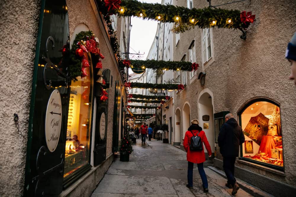 Handcrafted colorful holiday decoration at Goldgasse or Golden Street, old town, traditional advent, green Christmas tree branches outdoors in the center of Salzburg, Austria, 