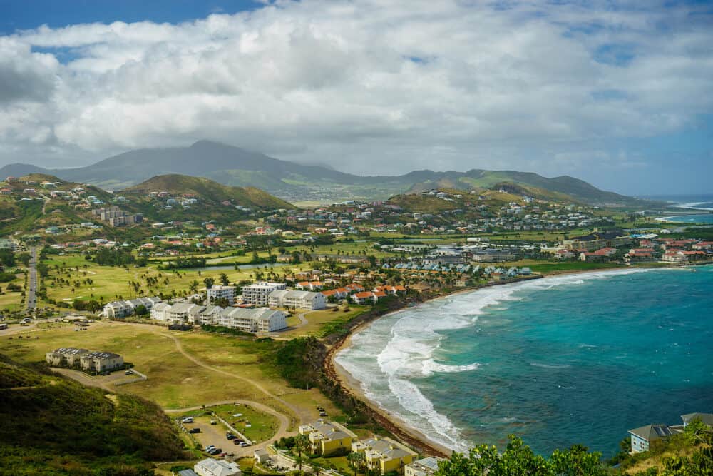 A view over St. Kitts Island with residential area and beaces on the foreground and lush green hills on the background