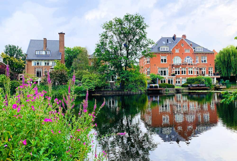 Beautiful houses along the river in Vondelpark Amsterdam, Netherlands. House reflection in the water. Home in a river. Private cottage or summer house. House on a river.