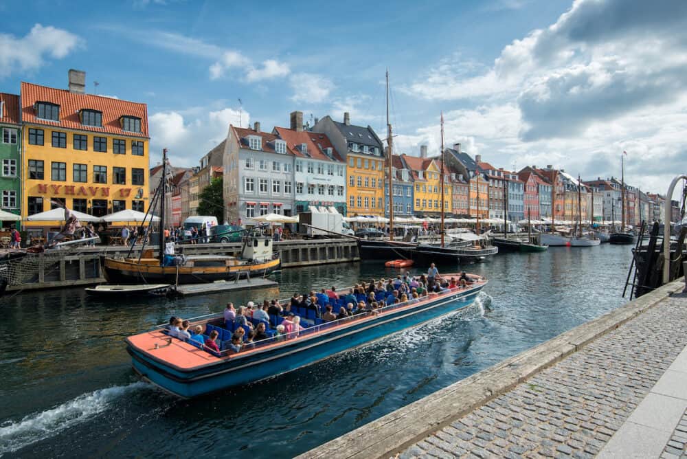 COPENHAGEN, DENMARK -A tour boat leaves Nyhavn for sightseeing on August 21, 2014 in Copenhagen. Nyhavn is a 17th-century waterfront, canal and entertainment district and a major tourist attraction in Copenhagen.