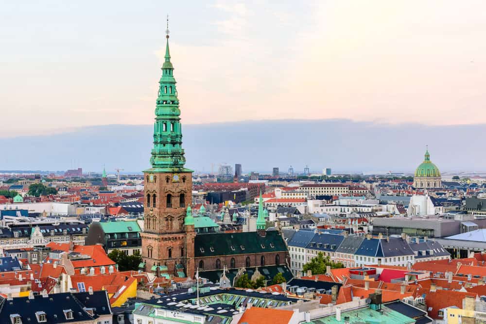 Copenhagen skyline by evening. Denmark capital city streets and danish house roofs panoramic view from top of Christiansborg palace.. Copenhagen old town Nikolaj Church spiel and Amalienborg dome.