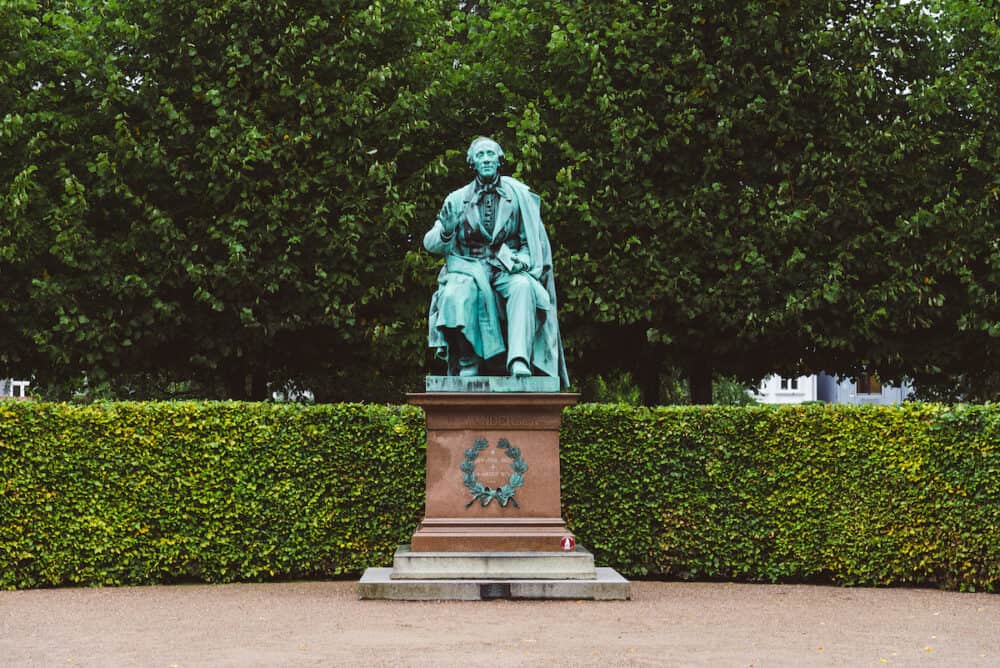 Copenhagen, Denmark -  Hans Christian Andersen statue in Rosenborg garden. Bronze sculpture of famous danish fairy tale writer amid green plants.