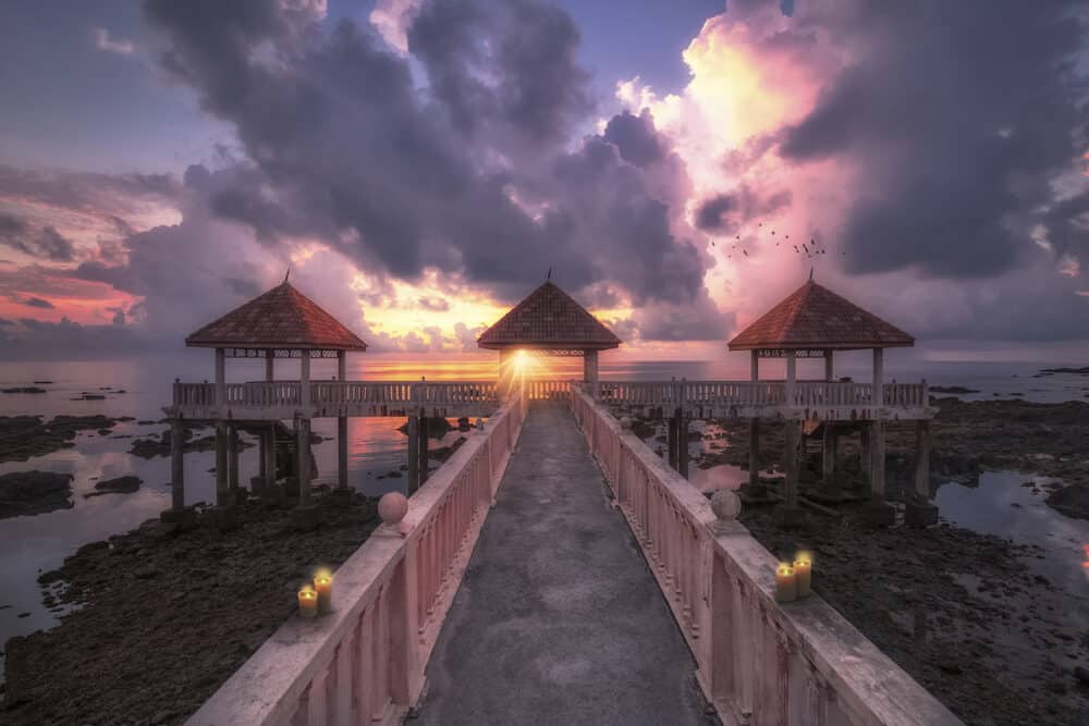 A beautiful sunrise at Desaru beach in johor through the dearu long jetty showing the colorful sky and the candles at the edges of the jetty