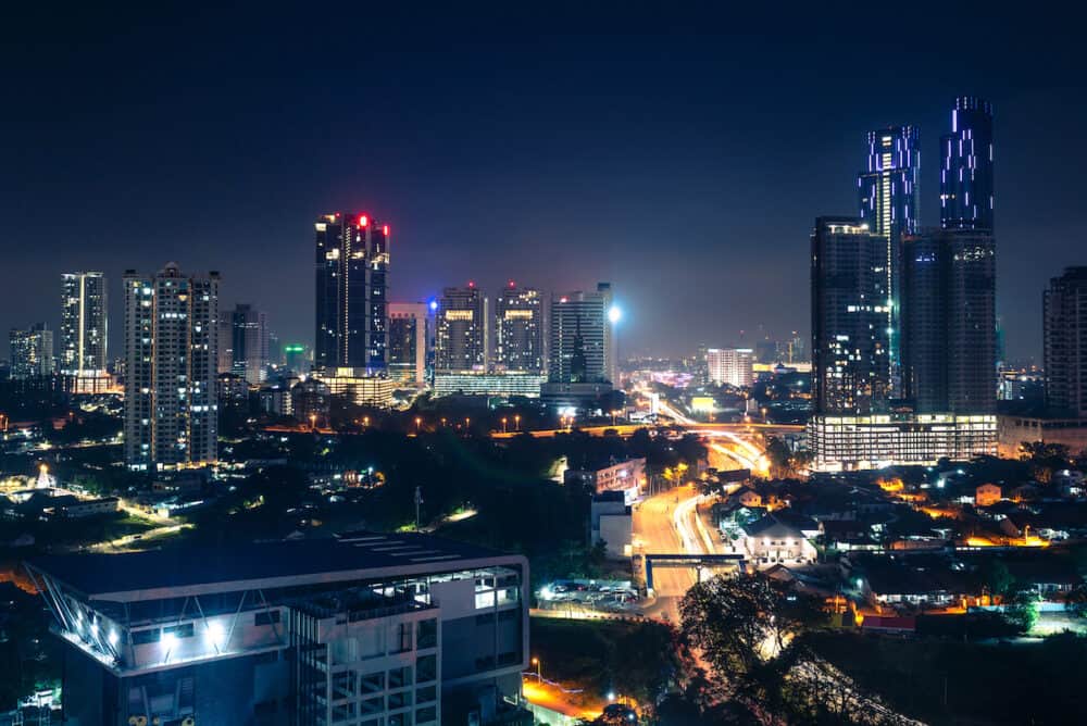 Johor Bahru, Malaysia, at night. Malaysian city with traffic on highway and modern business buildings and hotels in downtown. Scenic urban skyline and cityscape. Aerial view.