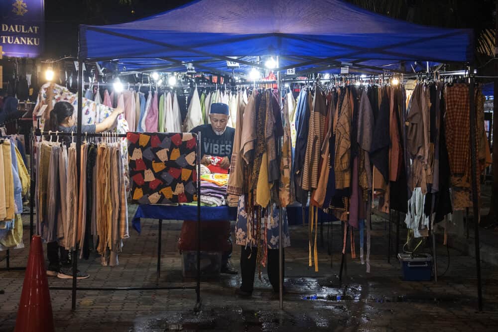 Johor Bahru, Malaysia-  Unidentified customer choosing T-shirt in the night market in Johor Bahru, Malaysia. Night markets are great for looking to experience the local lifestyle.