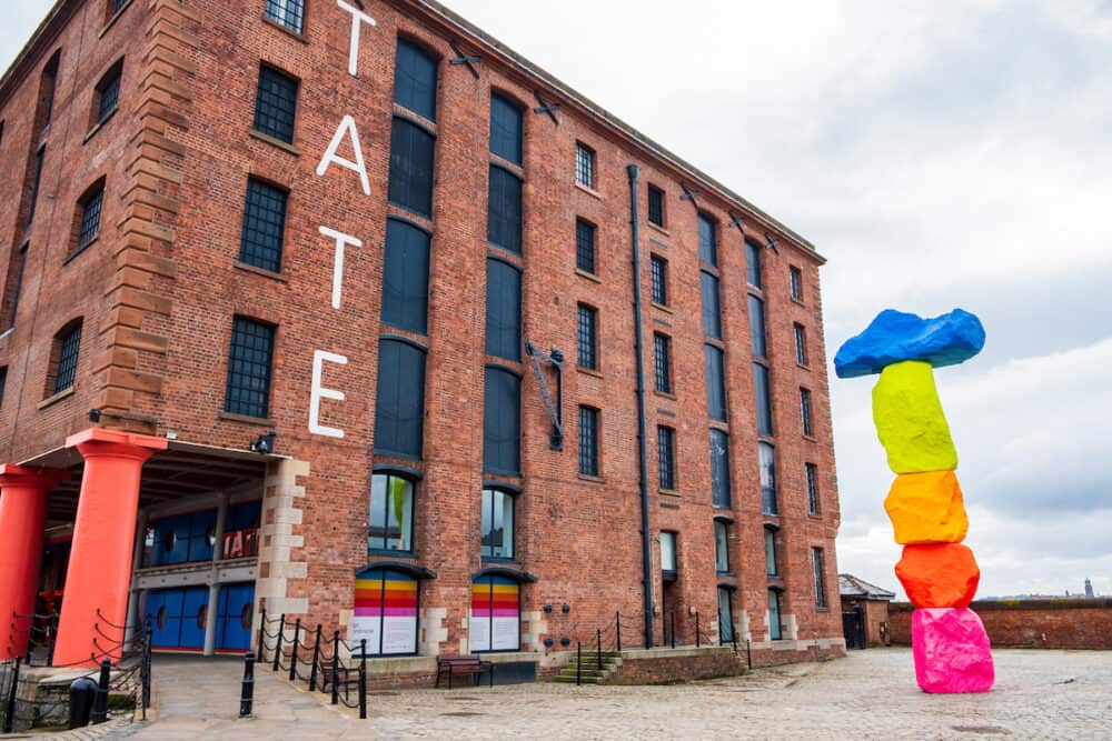 Liverpool, United Kingdom - Exterior of Tate Liverpool art gallery in the Albert Dock Area in Liverpool, Merseyside, with a sculpture by Ugo Rondinone named Liverpool Mountain in sight.