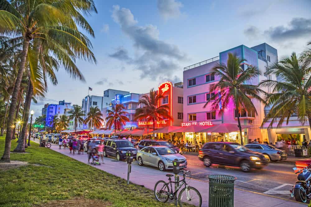 MIAMI USA - people enjoy Palm trees and art deco hotels at Ocean Drive by night. The road is the main thoroughfare through South Beach in Miami USA.