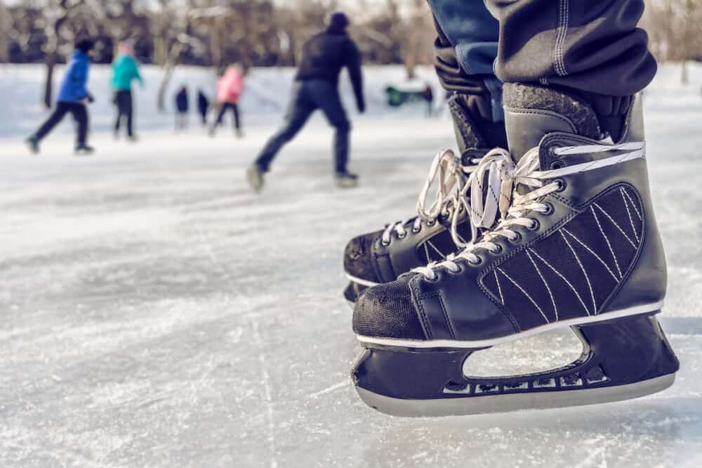 Close-up of ice skating shoes on a rink with people skating in the background