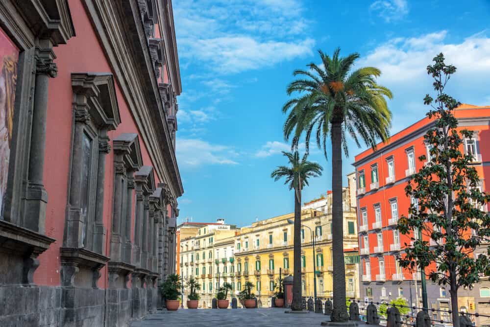 Colorful and beautiful architecture with palm trees in front of the National Archaeological Museum in Naples, Italy