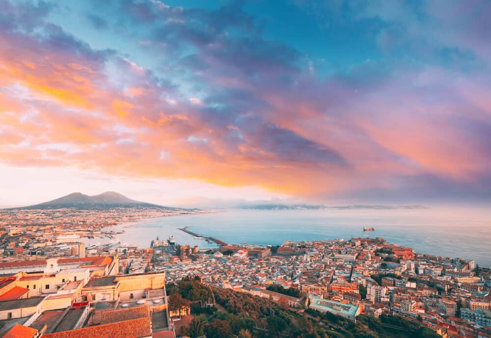 Naples, Italy. Top View Skyline Cityscape City In Evening Sunset. Tyrrhenian Sea And Landscape With Volcano Mount Vesuvius Naples, Italy. Top View Skyline Cityscape City In Evening Sunset. Tyrrhenian Sea And Landscape With Volcano Mount Vesuvius