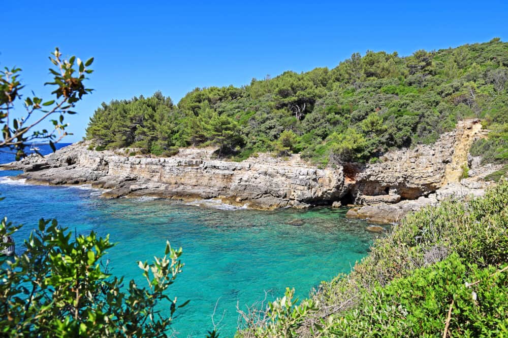 beautiful bay in croatia on the adriatic sea with stone cliffs and turquoise blue water, popular touristic destination in istria, landscape shot of stoja beach in pula
