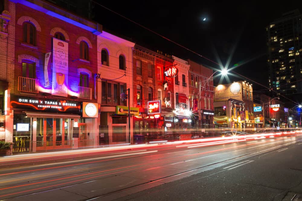TORONTO CANADA -  A view of buildings down King Street West at night showing restaurants and bars