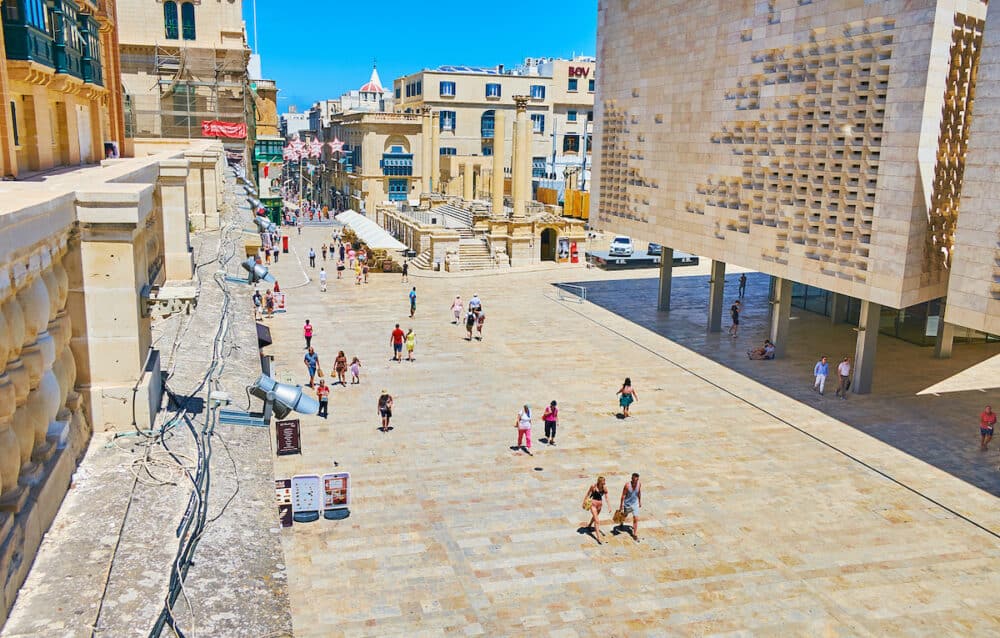 VALLETTA, MALTA -  Busy square in front of the ruins of Royal Opera House with columns, the crowd of people walks along Republic street, lined with old edifices in Valletta.