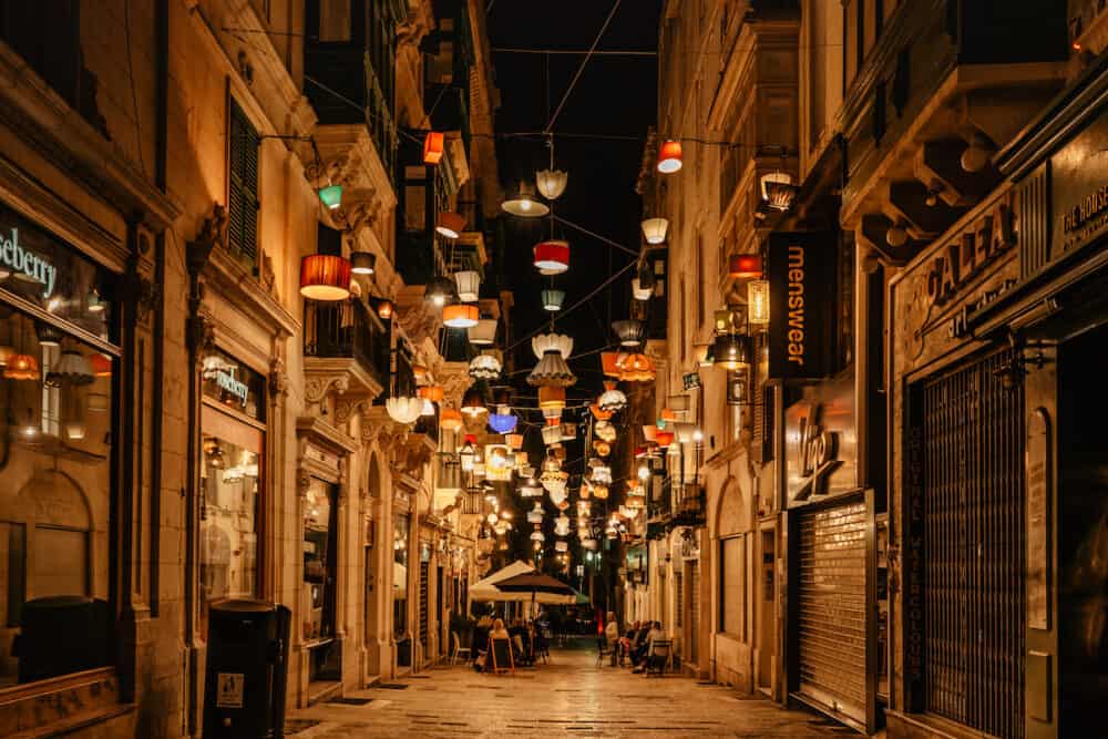 Valletta,Malta-Evening street with bars,shops and restaurants illuminated by colorful vintage lanterns.Night city life.Street festive lighting,people having fun on vacation