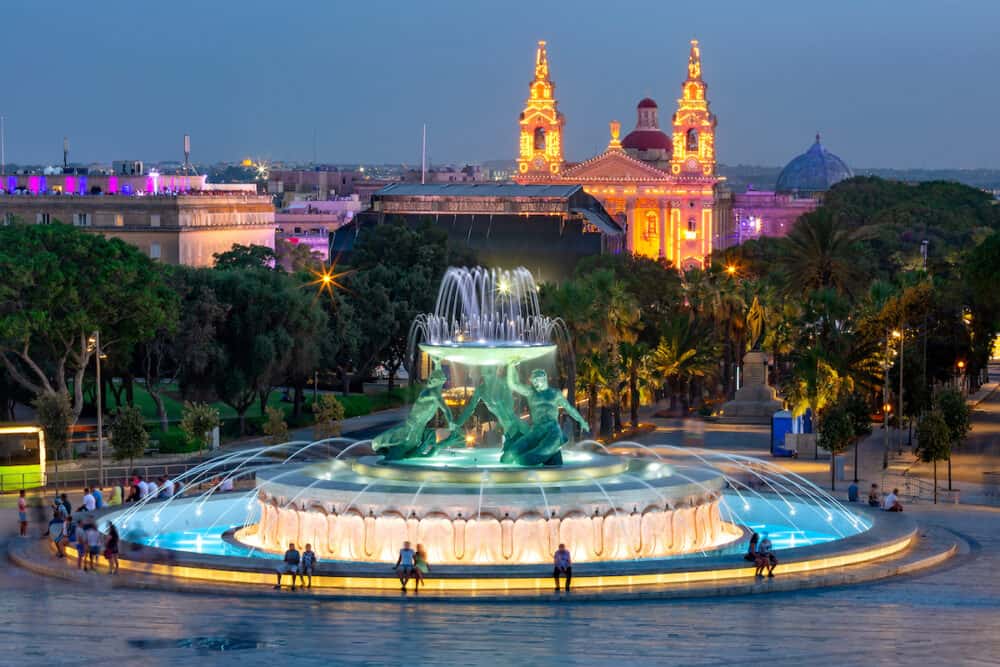 Sizable landmark Triton Fountain, featuring multiple bronze tritons and St. Publius church in Old Town of Valletta, Capital city of Malta