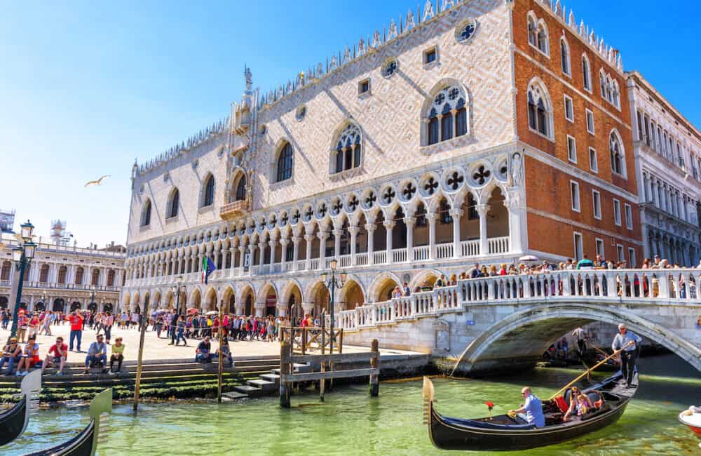 Venice, Italy - Doge`s Palace by San Marco in Venice. It is one of the top tourist attractions of Venice. Beautiful view of the Venice embankment with people and gondola in summer.