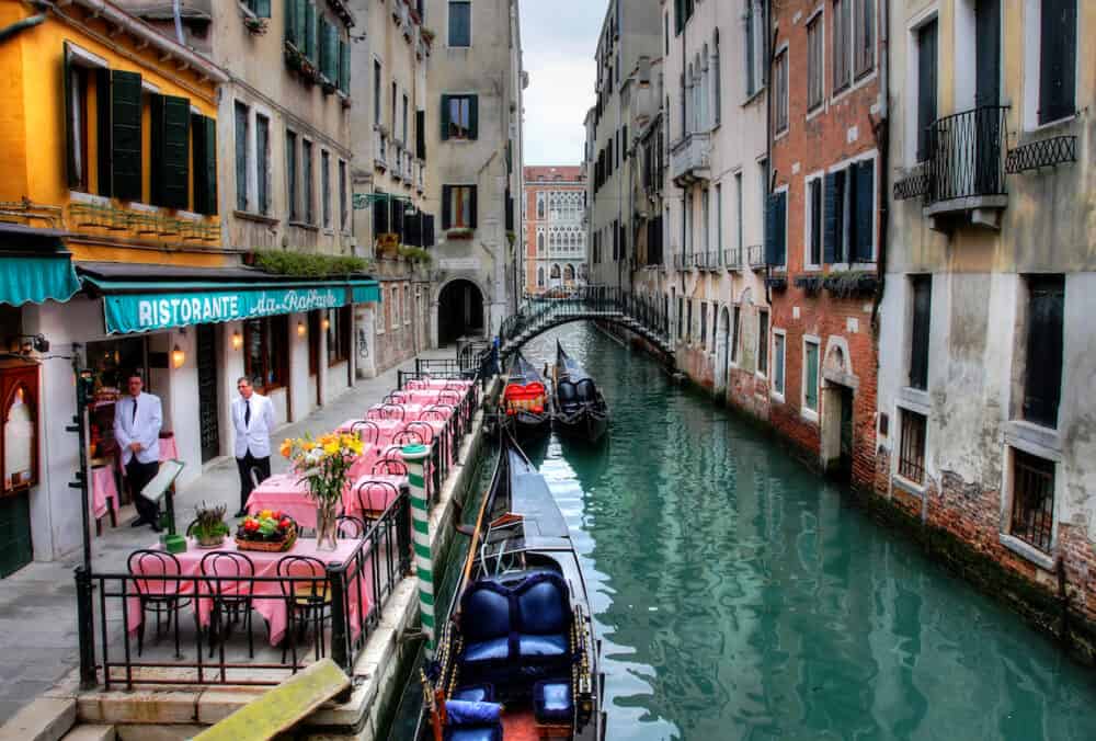 Small restaurant on venetian canal among old houses in Venice, Italy.