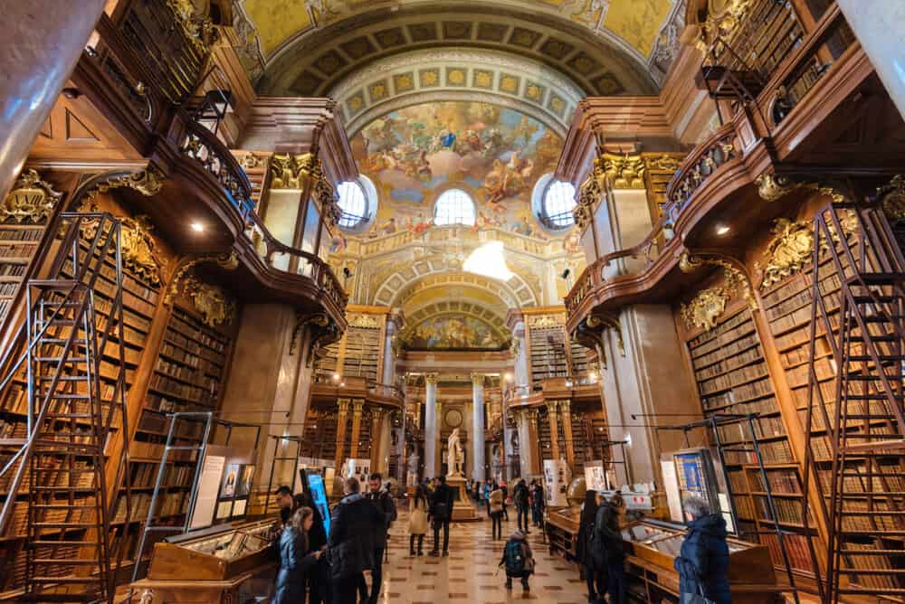 Vienna, Austria - Interior of Austrian National Library - old baroque library of Hapsburg empire located in Hofburg Palace. Grand Hall with lot of books and walking tourists.