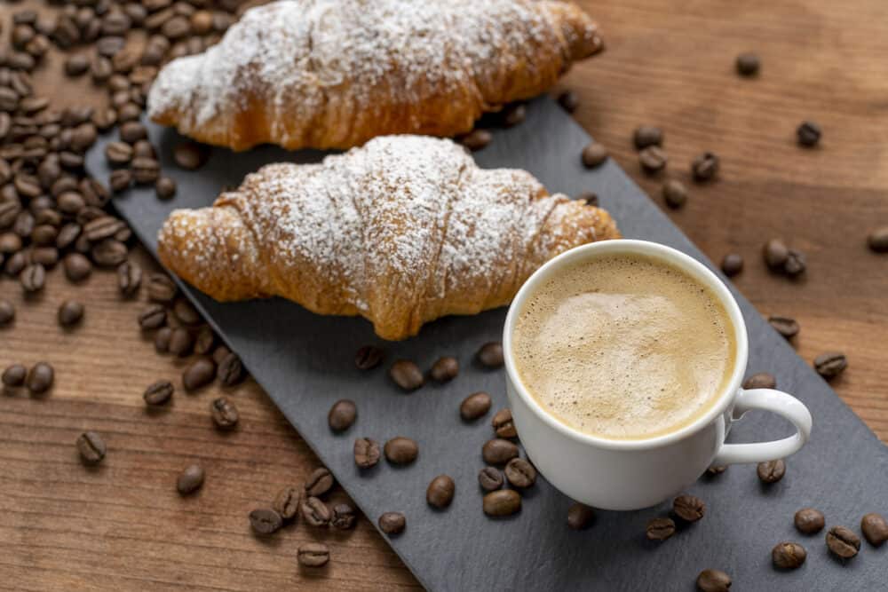 White coffee cup, croissants on wood table background, selective focus. Breakfast concept