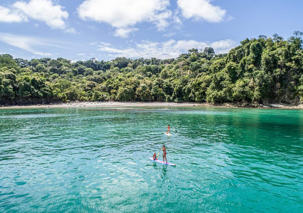 Manuel Antonio Costa Rica - SUP Stand up Paddle boarding in blue bay with empty beach Central America
