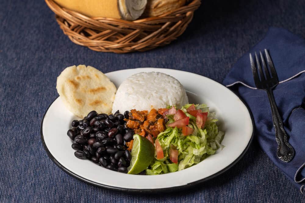 Casado, typical Costa Rican dish with rice, beans and vegetables in white plate.