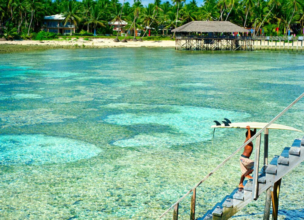 Unidentified young surfer carrying surfboards at Cloud Nine surf point in Siargao Philippines