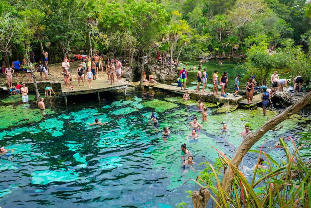 QUINTANA ROO, MEXICO - : Locals and tourists enjoying an open air cenote at the Yucatan jungle in Mexico