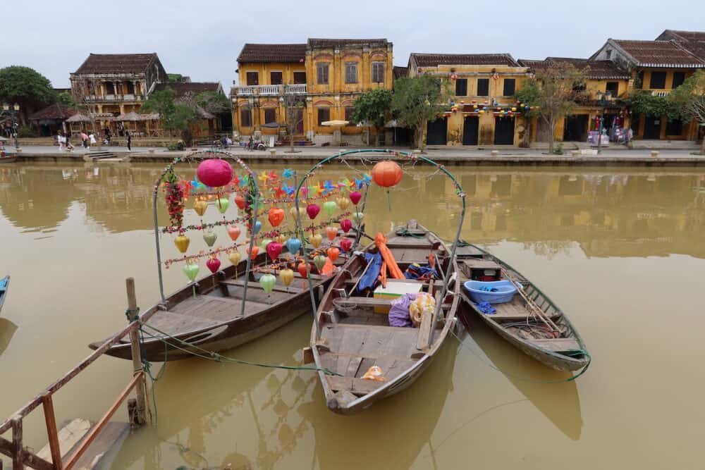 Three boats adorned with lanterns on the Thu Bon River in Hoi An